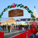 Feira de Natal em vila decorada com luzes festivas.