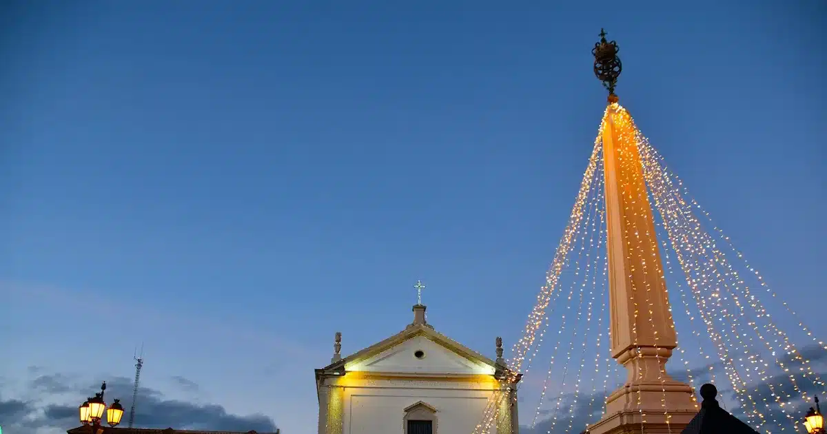 Igreja e coluna iluminada ao entardecer.