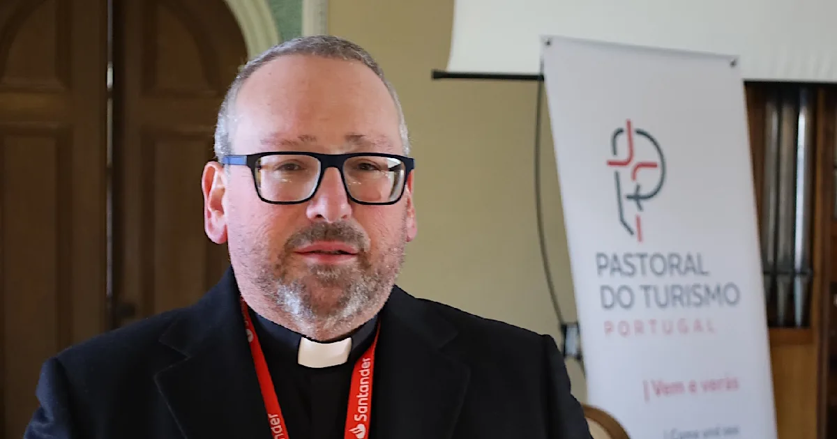 Homem ao lado de banner "Pastoral do Turismo".