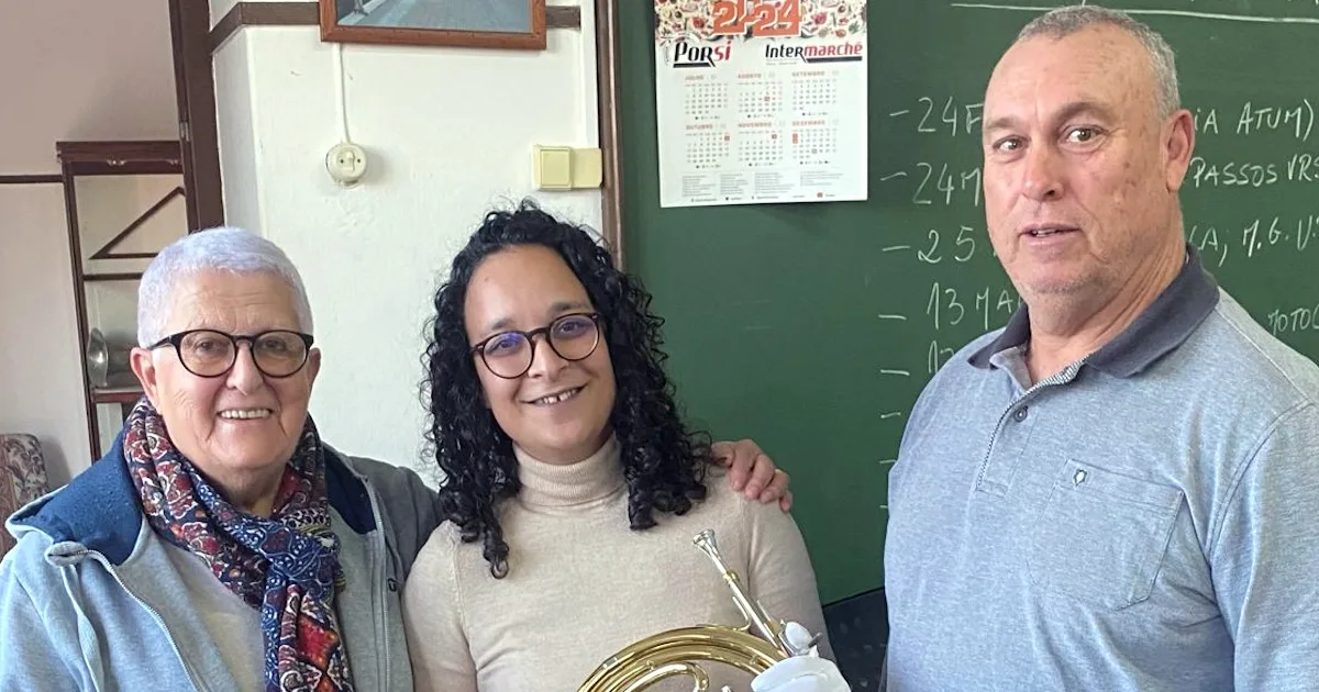 Três pessoas sorrindo em sala de aula.