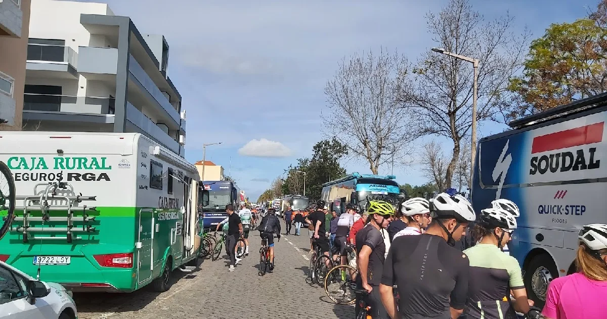 Ciclistas e autocarros de equipas em evento desportivo.