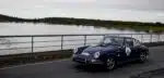 Porsche clássico azul junto a lago.