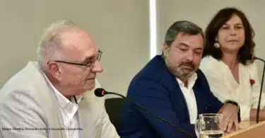 Três pessoas participando em painel de discussão.