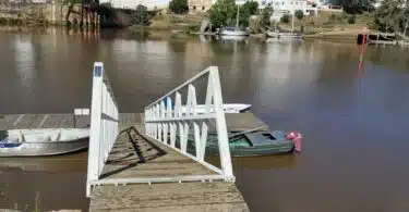 Doca fluvial com barcos e passadiço em madeira.