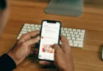 man holding phone while leaning on table